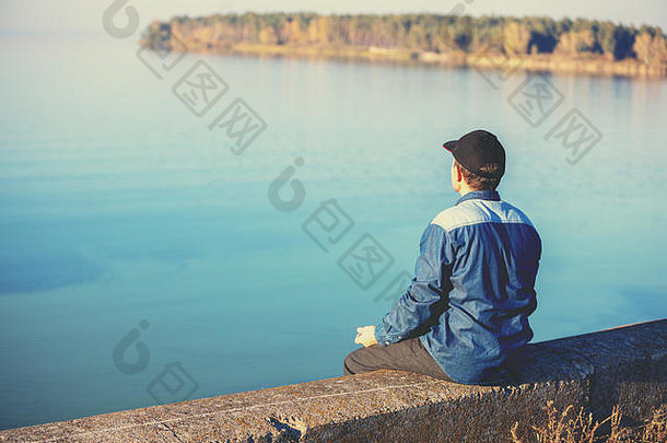 男人。坐在混凝土路堤风景如画的湖晚上