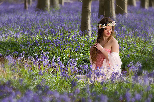 无辜的年轻的女人粉红色的仙女衣服春天蓝铃花森林