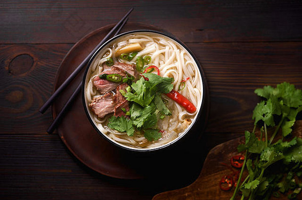 越南传统的汤巨像牛肉新鲜的香菜黑暗木背景
