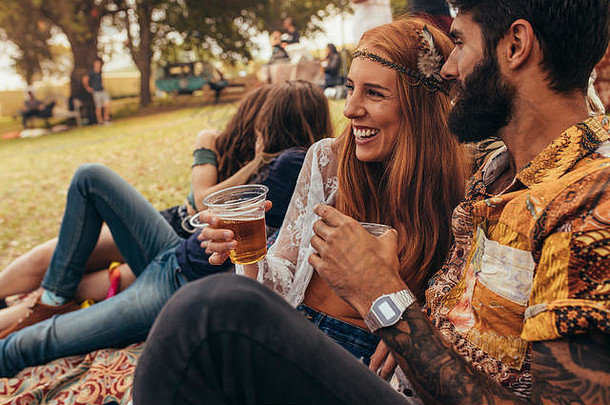 微笑夫妇啤酒坐着公园享受夏天节日快乐男人。女人朋友背景