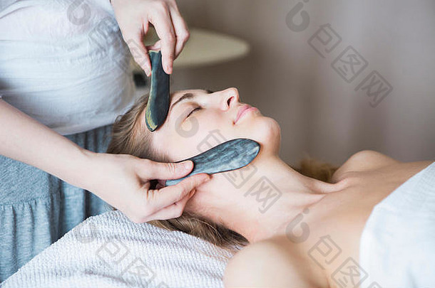 年轻的女人脸刮痧疗法治疗亚洲美诊所