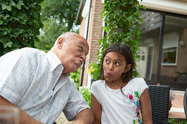 肖像祖父可爱的年轻的大女儿坐着花园拉有趣的脸夏天阳光