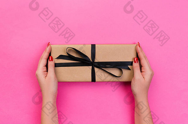 女人手给包装情人节假期手工制作的现在纸黑色的丝带现在盒子装饰礼物粉红色的表格前