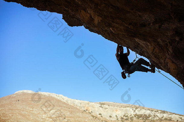 年轻的男人。攀爬天花板洞穴蓝色的天空