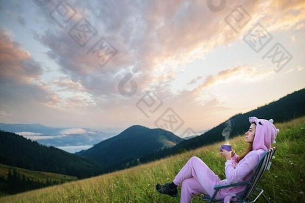 年轻的女孩粉红色的龙服装喝咖啡坐着椅子前山难以置信的山景观日出女孩