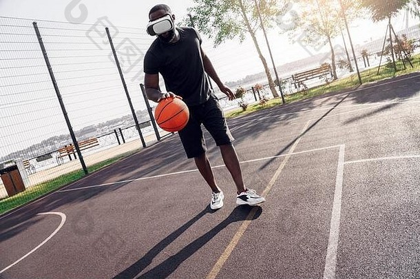 在户外活动非洲男人。耳机玩篮球法院集中