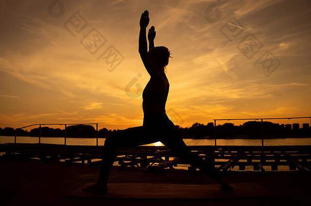 女人练习瑜伽<strong>日</strong>落维拉巴德拉萨那战士构成