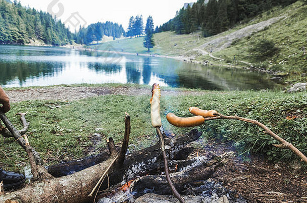 木棒烧烤烧烤香肠壁炉前面山湖