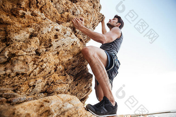 年轻的浅黑肤色的女人男人。攀爬自然岩石墙