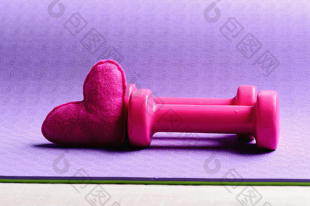 杠铃粉红色的爱象征关闭哑铃使粉红色的塑料软玩具心紫色的纹理背景复制空间爱体育<strong>健身</strong>设备健康的生活方式概念