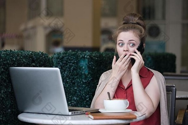 年轻的高加索人女人咖啡馆咖啡移动PC会说话的电话震惊了惊讶表达式