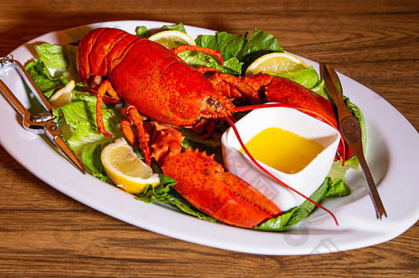 新鲜的煮熟的龙虾床上绿色柠檬片融化了黄油吃餐具服务白色陶瓷盘木表格