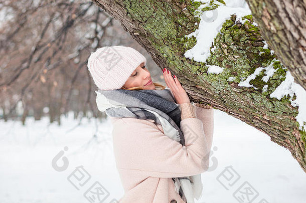 年轻的女人站树树干冬天