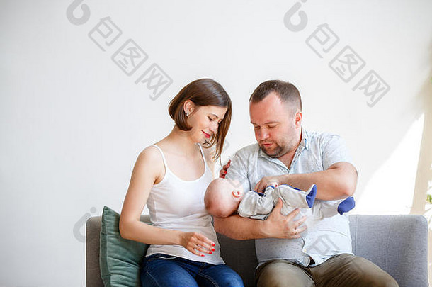 照片年轻的父母新生儿婴儿坐着沙发