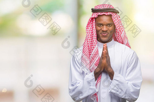 年轻的阿拉伯语非洲男人。穿传统的阿拉伯人的头巾孤立的背景祈祷手宽恕微笑自信