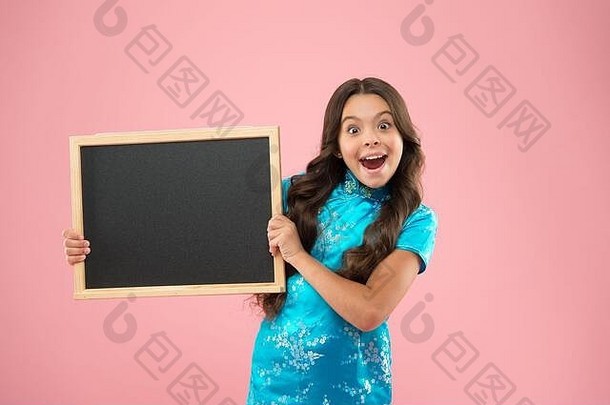 快乐女孩持有黑板上粉红色的背景快乐的孩子持有广告董事会学童教训黑板上广告文本复制空间回来学校市场营销运动