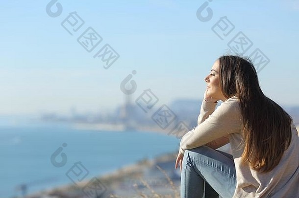 一边视图肖像女人冥想放松坐着在户外海岸城市背景