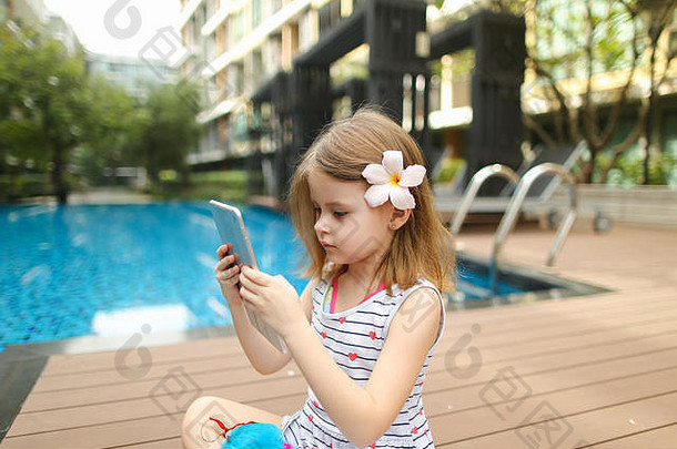 孩子女孩使照片平板电脑坐着关闭游泳池我们