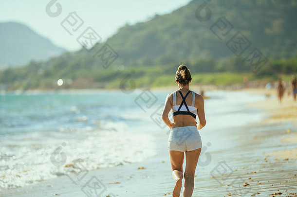 年轻的女人慢跑者健身衣服海洋海岸晚上慢跑新鲜的空气美丽的海洋海岸理想的challen