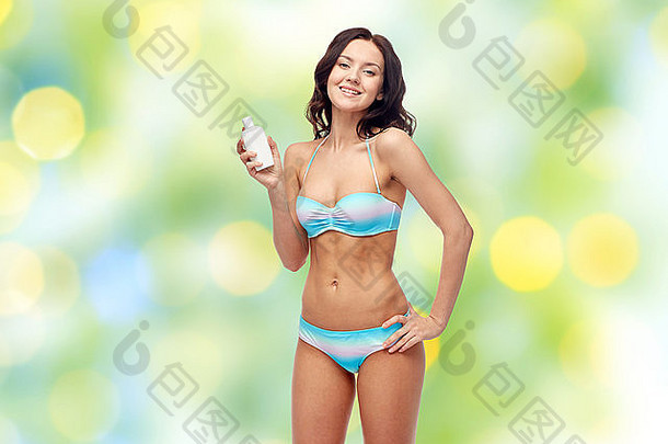 快乐年轻的女人泳衣持有防晒霜