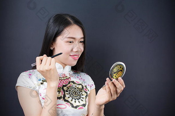 美丽的年轻的亚洲女人应用化妆脸