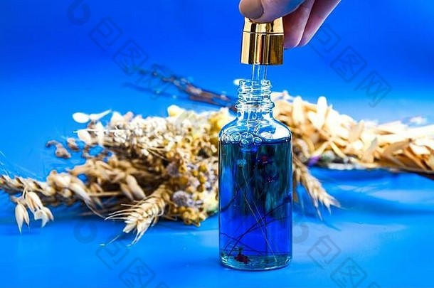 反老化血清玻璃瓶下降蓝色的背景干花面部液体血清胶原蛋白肽角质层石油