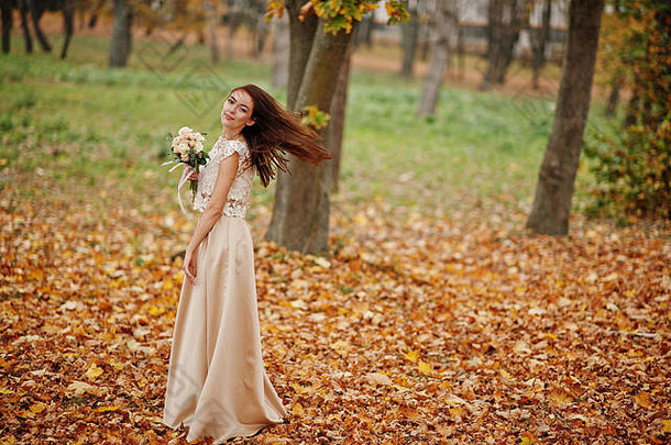 令人惊讶的是女孩伴娘金衣服花束手秋天公园