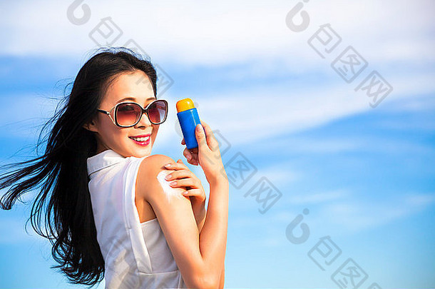 年轻的女人应用太阳保护乳液