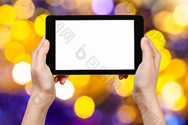圣诞节聚会，派对概念手平板电脑减少屏幕背景黑暗黄色的紫罗兰色的闪烁的圣诞节