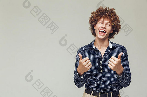 照片年轻的快乐复古的男人。穿着衬衫站摆姿势孤立的相机显示拇指