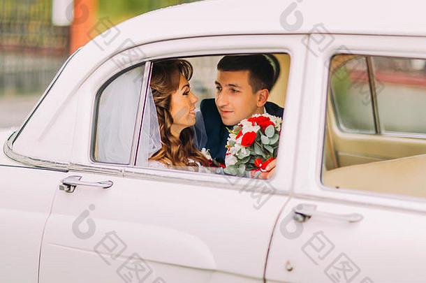 快乐新婚夫妇坐着后座古董车