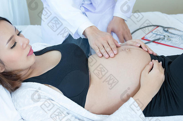 医生触碰怀孕了女人的肚子咨询房间