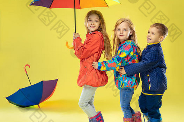 完整的长度肖像明亮的时尚孩子们雨衣伞彩虹颜色黄色的工作室背景秋天春天时尚孩子们可爱的时尚的女孩男孩有趣的