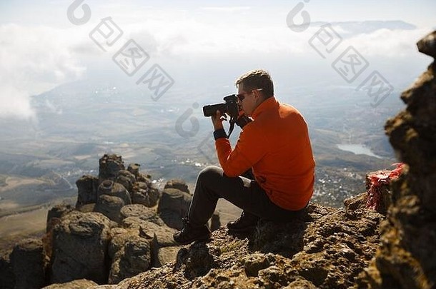 年轻的专业旅行者男人。数码单反相机相机拍摄户外神奇的山景观徒步旅行者坐在岩石<strong>高峰会</strong>