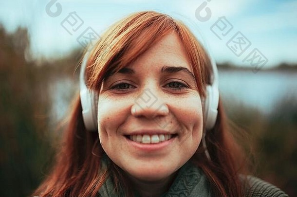 年轻的女人采取自拍智能手机湖耳机