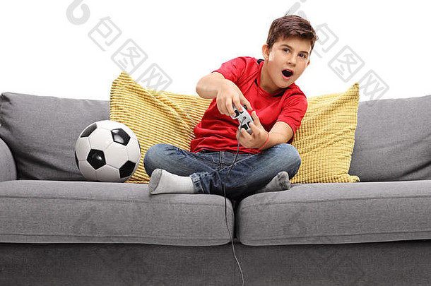 男孩玩足球视频游戏坐着沙发孤立的白色背景
