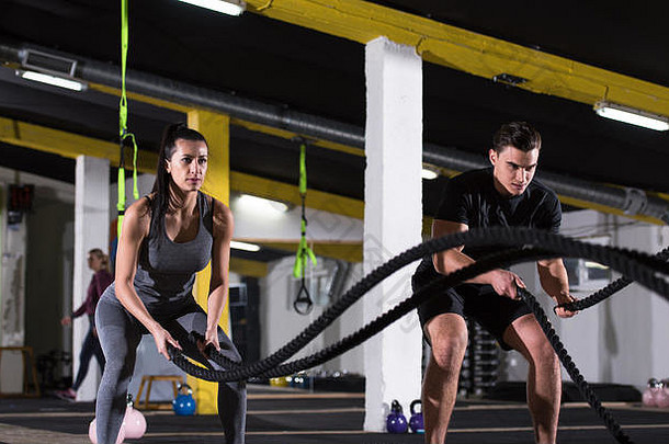 年轻的适合体育夫妇工作功能培训健身房战斗绳子交叉健身锻炼