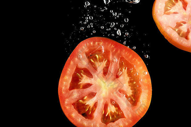 番茄片下降水黑色的背景