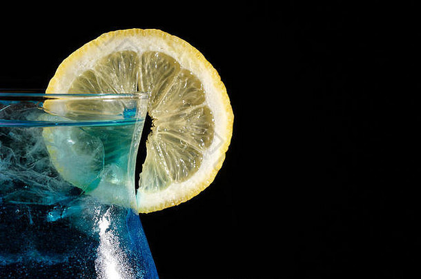 特写镜头蓝色的库拉索岛鸡尾酒片柠檬黑色的背景