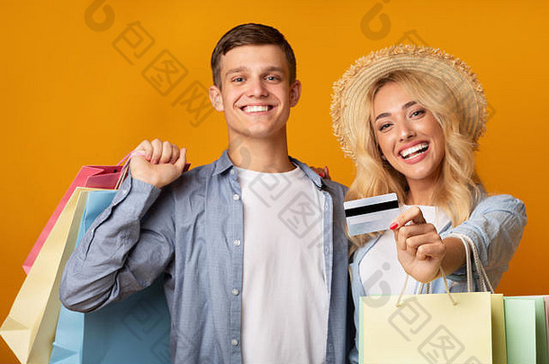 快乐的年轻的夫妇推荐信贷卡持有购物袋