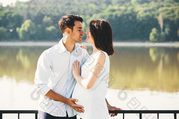 爱年轻的夫妇快乐等待婴儿骄傲父亲触碰妻子的肚子美丽的景观背景复制空间