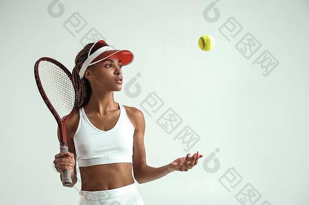 准备好了玩肖像年轻的非洲女人体育衣服持有网球球拍肩膀扔网球球站灰色背景网球概念专业体育运动