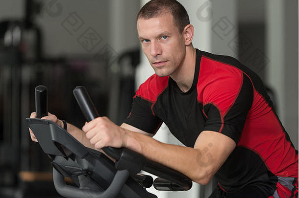 健身男人。锻炼自行车现代健身中心