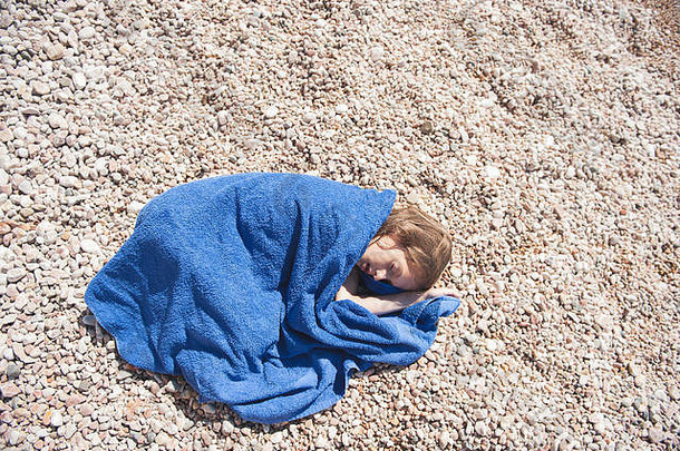 睡觉女孩包装蓝色的毛巾说谎夏天卵石海滩热太阳光