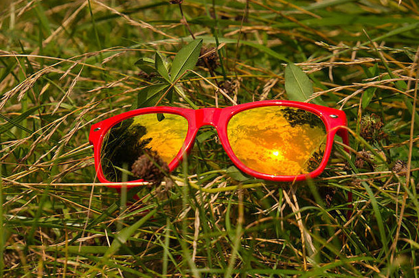 云太阳反射玻璃太阳镜红色的塑料框架草地草