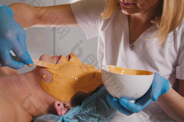 年轻的女通过治疗水果面具面部水疗中心沙龙