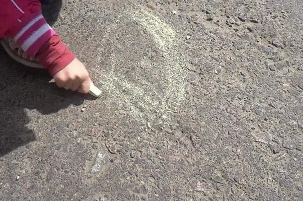 婴儿手画彩色的用粉笔写人行道上
