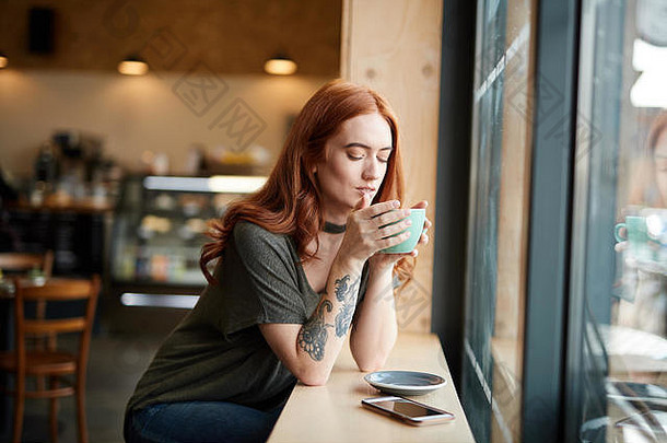 红色的头女孩手臂纹身坐着咖啡馆窗口利物浦