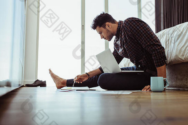 自由职业者纸工作移动PC电脑首页男人。工作移动PC电脑坐着地板上咖啡杯