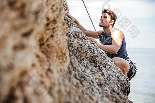年轻的浅黑肤色的女人男人。攀爬自然岩石墙